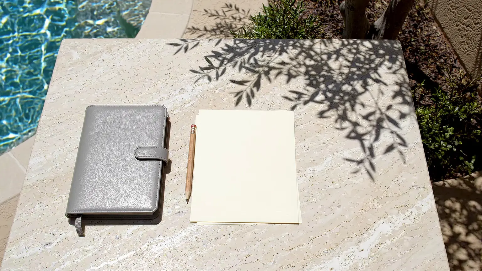 Blank paper, a notebook and an envelope beside a pool